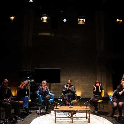 A group of people sat on chairs in a semicircle on a stage