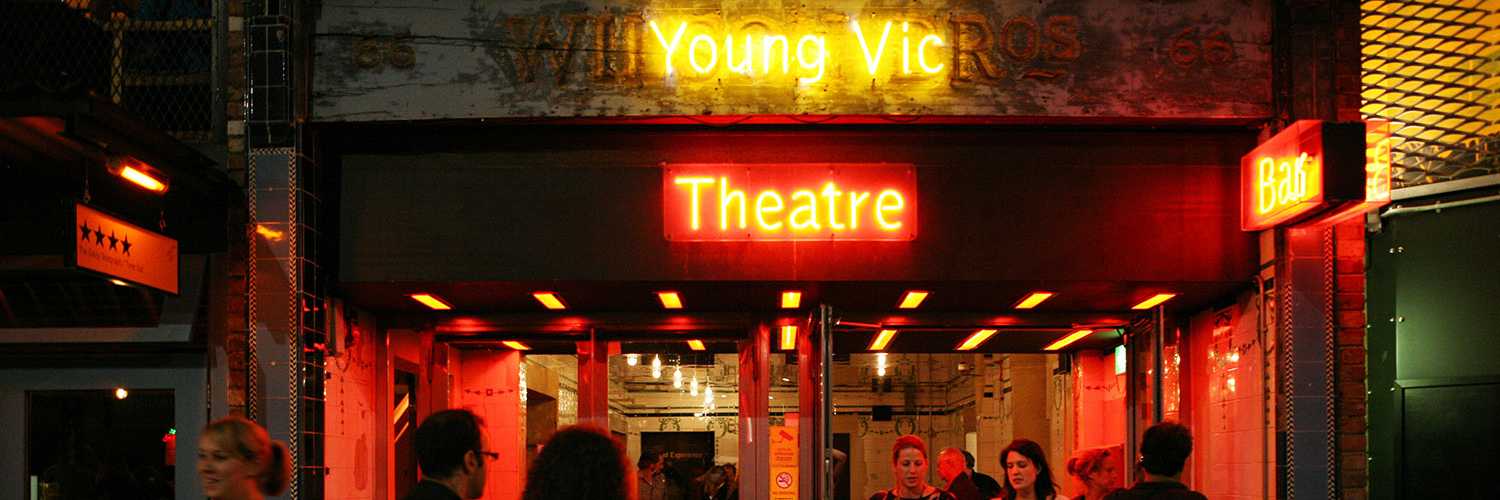 Entrance of theatre, Young Vic in yellow neon lettering and theatre in red neon lettering.