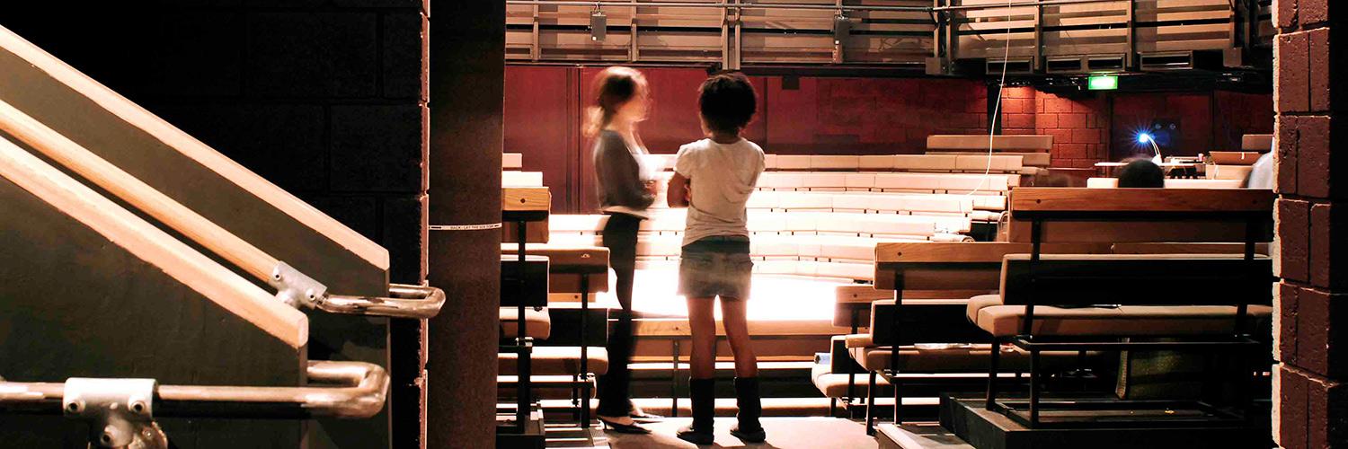 Two people speak to each other in the Young Vic main auditorium