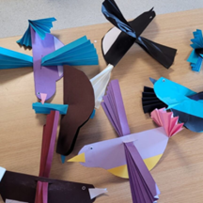 A selection of colourful paper origami birds on a wooden desk. 