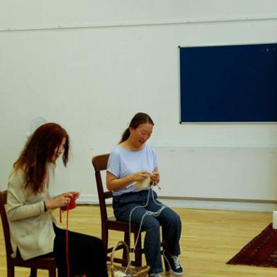 two people seating, knitting