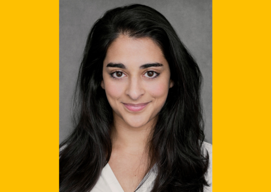 A headshot of a small, dark haired woman with mid length hair and dark brown eyes wearing a cream blouse.