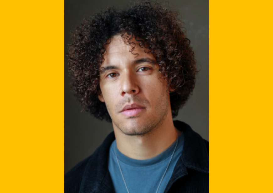 A headshot of a man of average height with light brown skin and a big afro