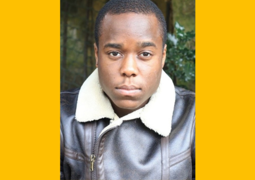 A headshot of a person with short dark hair wearing a brown leather jacket.