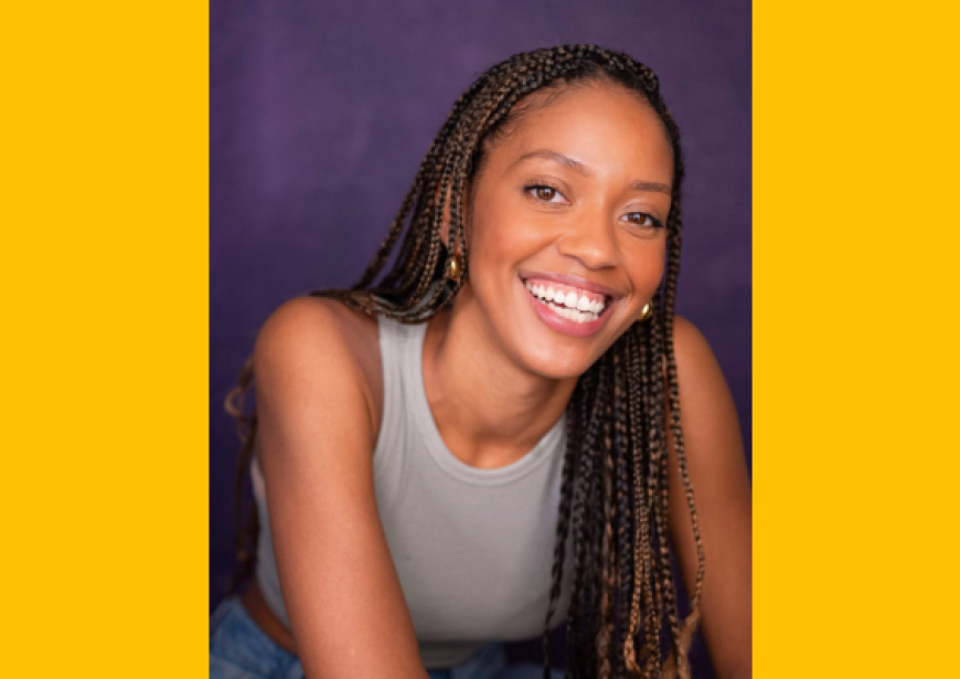 A headshot of a person with long braids wearing a white singlet.