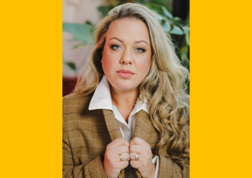 A headshot of a blonde woman wearing a white shirt and brown tweed blazer