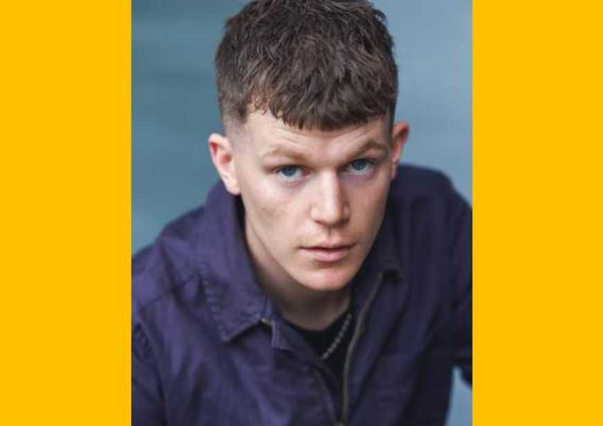 A headshot of a white man with short brown hair wearing a dark long-sleeved shirt