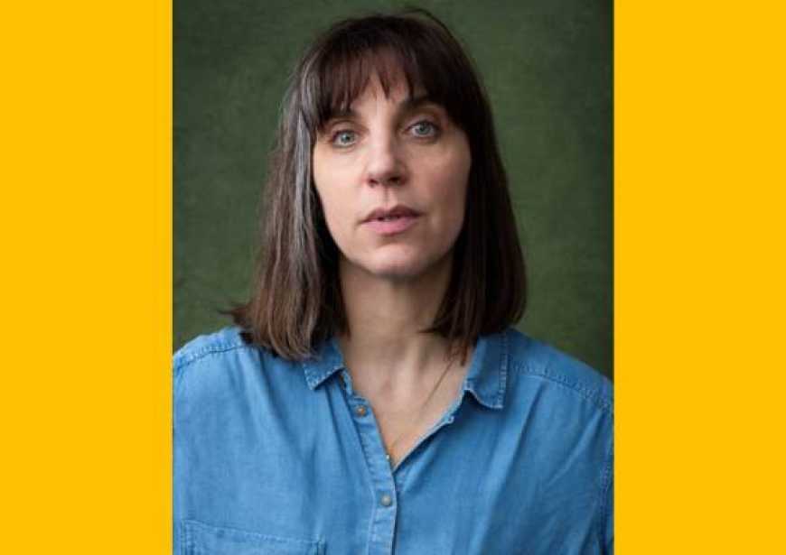 A white woman with brown hair and bangs wearing a blue shirt