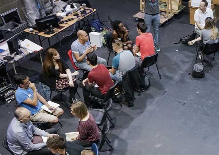 A group of people sat in a circle, facing each other in groups of two.