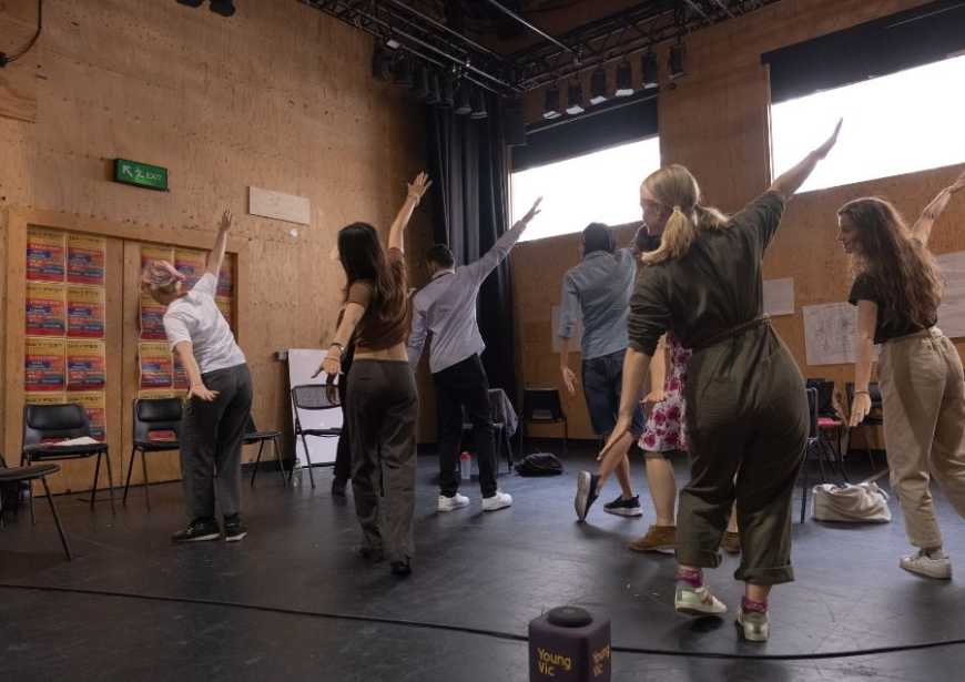 A group of people in a studio facing the same way with their arms extended as if flying.