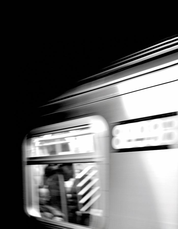 Black and white image of a train window, train has been captured in motion so image is slightly blurred.