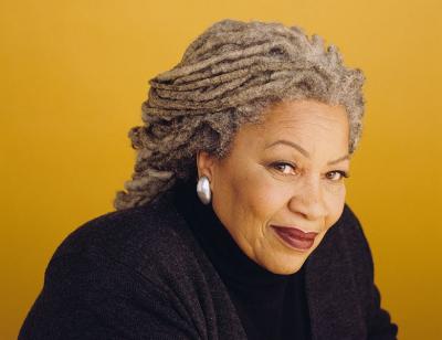 A colour photo of a smiling Toni Morrison against a yellow background